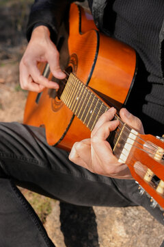 Close up hands of playing string guitar outdoors in autumn forest. Concept of sound therapy, mental health and wellness rituals. Calmness tranquility audio-sensory practices. Aura farming energy