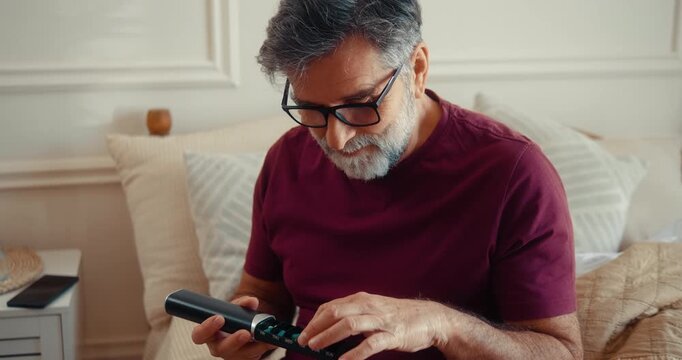 Senior man holding weekly pill organizer and taking medication or vitamins in the morning. Positive and healthy lifestyle scene showing daily routine, healthcare, wellbeing, and responsible habits 