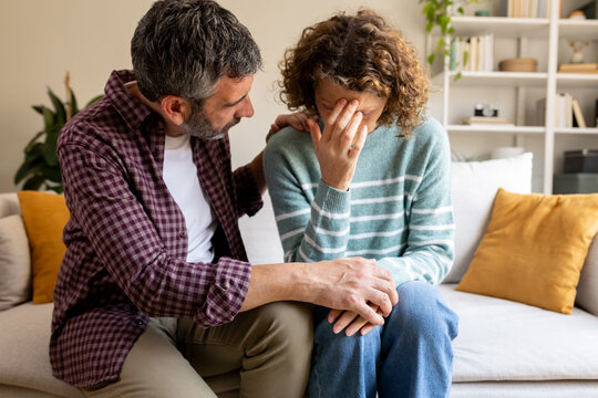 Man comforting sad woman expressing grief at home