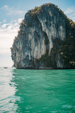 Towering limestone karst cliff rising from emerald sea near Koh Hong