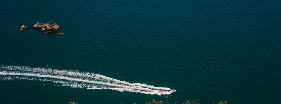Speedboat leaving wake in the Andaman Sea near small limestone islet