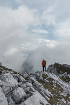 Hiker navigating a rocky, cloud-covered mountain peak