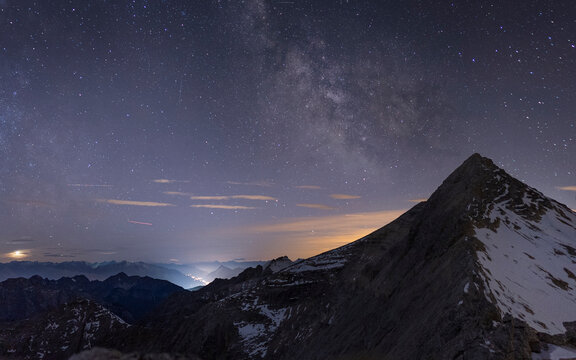Starry night sky and Milky Way over a mountain peak
