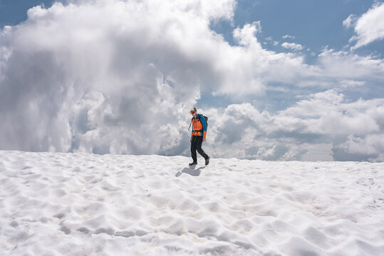 Hiker crossing a patch of snow in the mountains