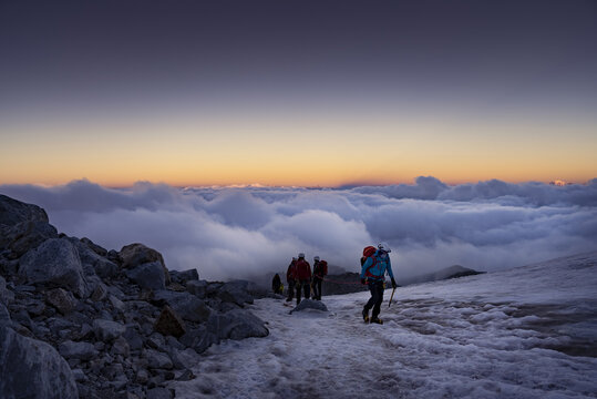 Climbers watching the sunrise from a rocky outcrop