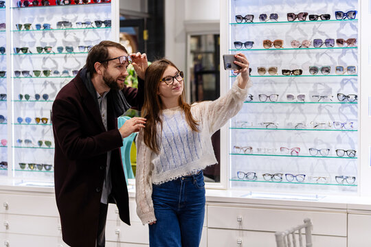 Father and daughter choosing glasses frame at an optician shop.