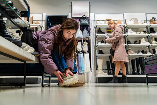 teenage girl tries on new winter boots in a shoe store.