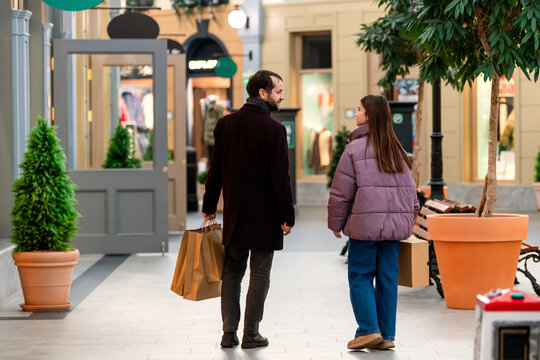 Father and Teenage Daughter Walking in Shopping Mall with Bags