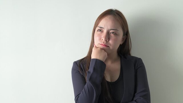 Portrait of a young happy Asian businesswoman against white background thinking
