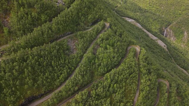 A Cyclist Follows Steep, Winding Switchbacks Through Dense Green Slopes Along Tusenmeteren, &Oslash;vre &Aring;rdal, Norway - Aerial Drone Shot