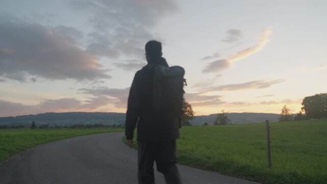 Young man with a backpack hiking at sunset in late summer, Switzerland