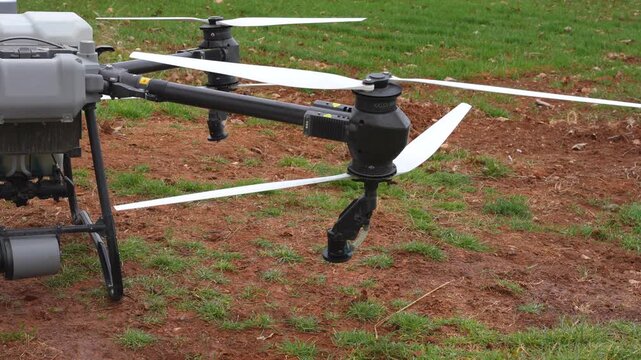 Close up shows agricultural drone arm releasing water vapor during preflight test near wheat field