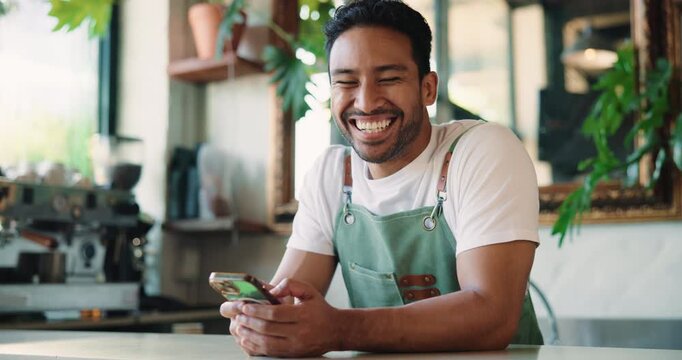 Texting, face and barista in cafe with phone, online gif or chat reaction on work break. Laugh, typing or Asian man in restaurant with technology, funny review or hospitality meme on website
