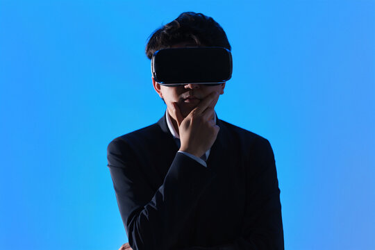 仮想空間に没入し顎に手を添えて考えるスタイリッシュなVRゴーグル姿の男性