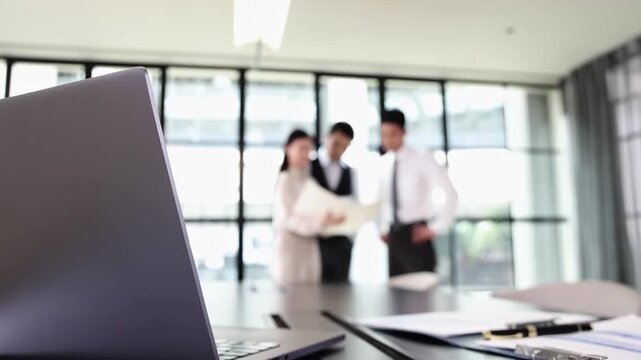 Group of company employees discussing work new project, exchanging ideas, reviewing documents standing in office during meeting, focused discussion leads to innovative solutions successful outcomes