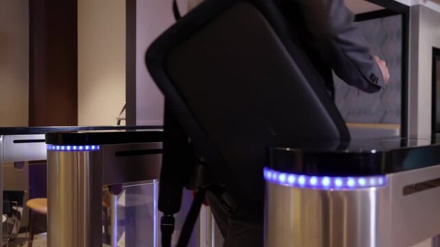 Man worker in formal suits walks through gates into business center using electronic pass card, entering office after lunch break talking and passing through automatic security turnstiles gateway