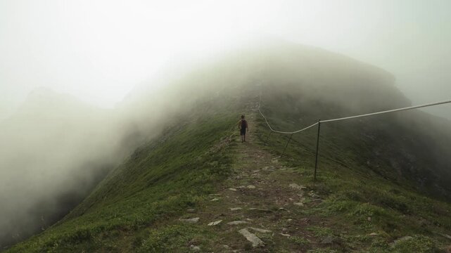 Hiker Hiking To The Peak Of Nyken Mountain On A Foggy Day In Oksnes, Nordland, Norway. - wide shot