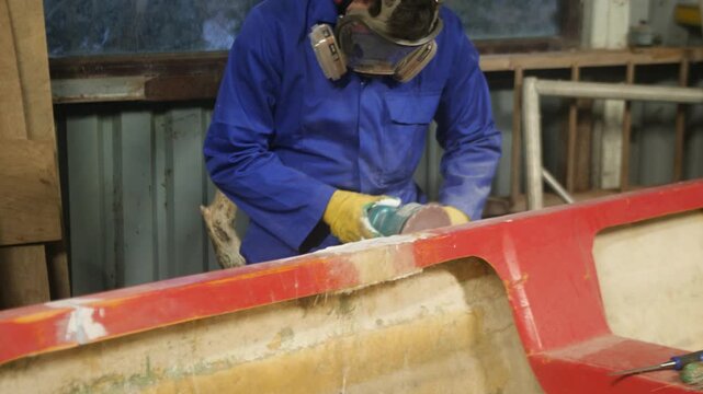 Sanding repaired gunwale of fiberglass fishing boat using orbital sander