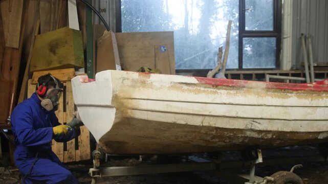 Sanding transom of fiberglass fishing boat using orbital sander