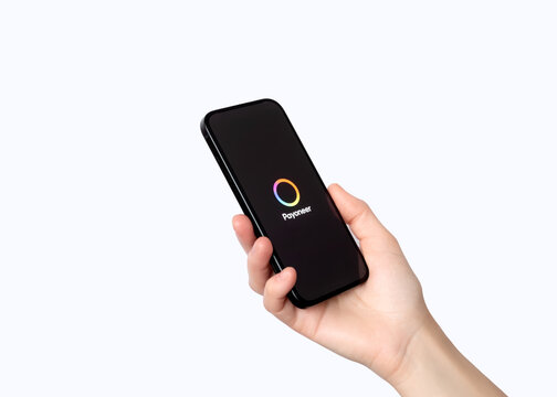 Hand holding smartphone with Payoneer mobile application loading screen