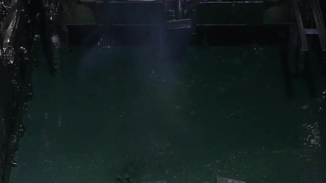 Overhead view of a vehicle frame fully submerged in a green cathodic electrodeposition tank