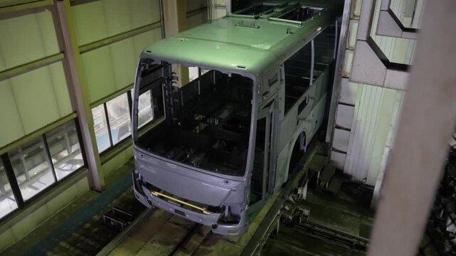 High-angle view of a bus body shell being transported through a modern assembly plant