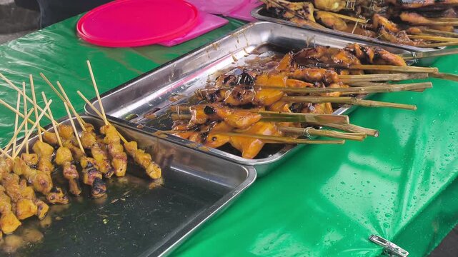 Traditional Ayam Percik is displayed on a table for sale. This marinated chicken is slow-grilled over charcoal to ensure a smoky aroma and rich, flavorful taste in every bite.