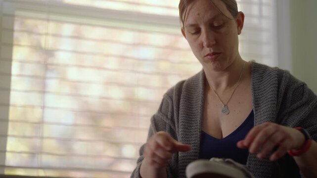 A woman unlacing her shoe to put on.