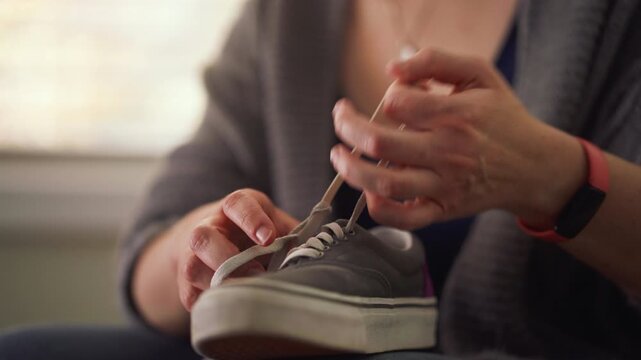Close up of a woman unlacing her shoe to put on.