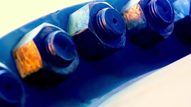 Macro view of metal bolts and nuts fixed on blue industrial metal surface