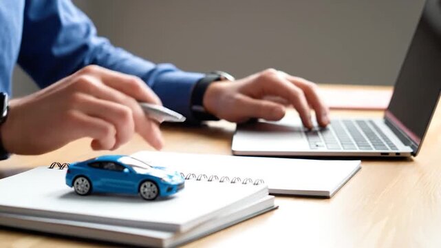 Close up hands typing on laptop and writing in notebook with blue car model on desk motion graphics for business finance and automotive concepts