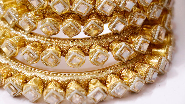 Typically made from a base metal like brass or mixed metal, which is then gold-plated. The stones are usually artificial Kundan, Polki, or pearls background