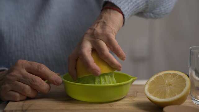 Close-up lifestyle clip of a grandmother&rsquo;s hand using a juicer to squeeze a lemon for lemonade at home.