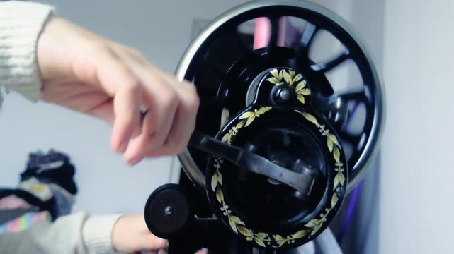 Extreme close up showing a child's small hands touching the intricate gold floral patterns on a century old vintage sewing machine in a home studio in Budapest Hungary with soft light in 2026.