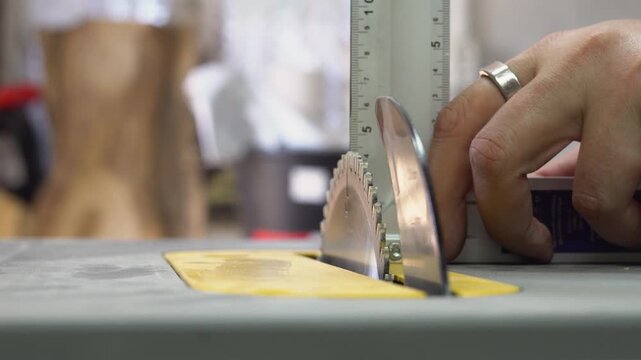 Close-up of hands measuring a table saw blade in a workshop setting