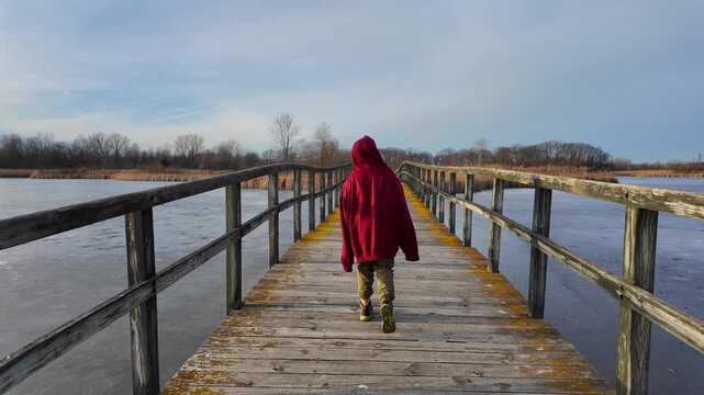 Person walking along wooden boardwalk over frozen water at Crosswinds Marsh, New Boston, Michigan, USA