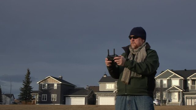 Middle aged man flies drone in city park, MCU in golden hour sunlight