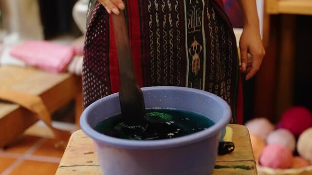 Artisan dips yarn into natural dye for handmade textile weaving