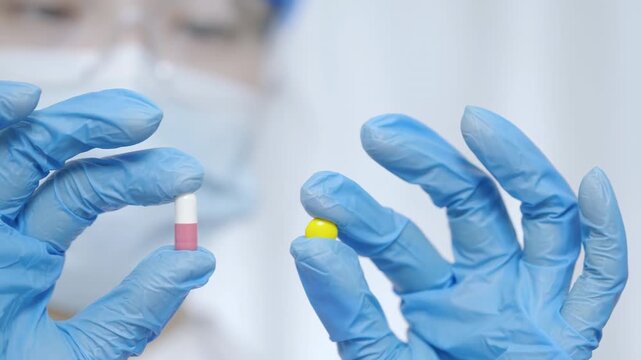 A faceless doctor with gloves holding colorful vibrant white pink and yellow drug pill capsule, medication in various shapes and sizes for health treatment and drug care concepts