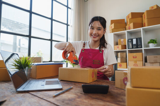 Asian woman packing boxes for online business shipping