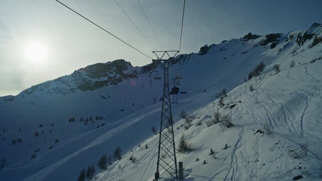 Scenic chairlift views above Anz&egrave;re with slight overcast skies and soft sun breaking through over the Swiss Alps and Rhone Valley. Moody alpine atmosphere, winter landscape, cinematic resort feel.