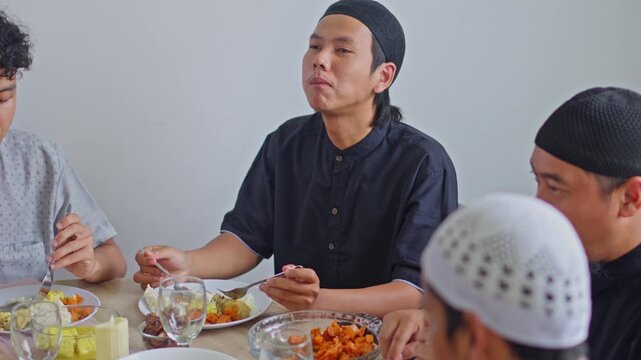 Muslim Family eating together at dining table while celebrating Eid Al-Fitr