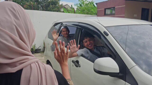 Happy family waving goodbye from car for Mudik homecoming journey