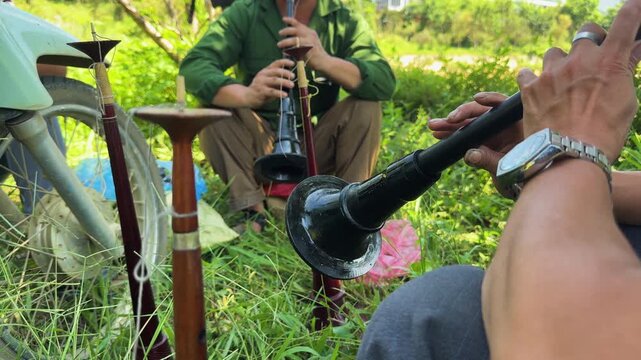 Local Hmong men play traditional Khen instruments at the bustling Bắc H&agrave; Sunday Market in Lao Cai, surrounded by the lush, green highland landscapes and plum orchards of Northern Vietnam.