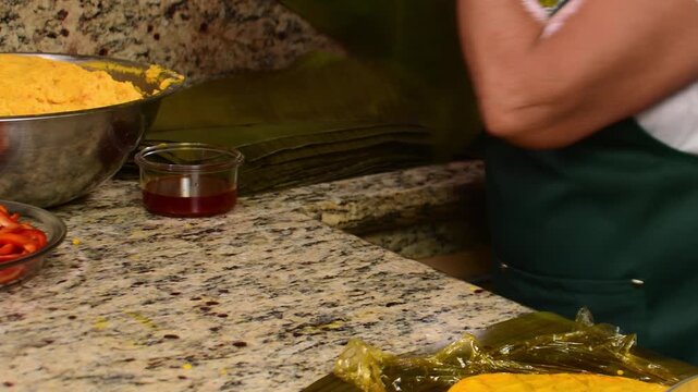 Close up of spreading yellow masa with onoto oil on banana leaf food