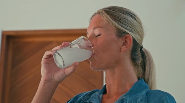 Caucasian fit blonde woman drinks a glass of water mixed with creatine powder