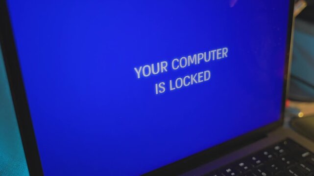 Extreme close up on computer screen message locked by hacker cybercrime attack. Laptop device is remotely accessed by spy or malware. Locking user out of computer with alarming alert message glitch