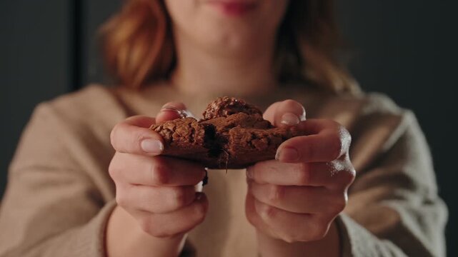 Woman breaking chocolate cookie to show soft inside slow motion