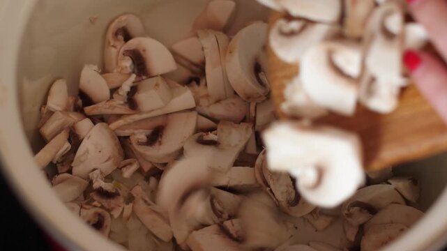 Slicing fresh champion mushrooms for cooking delicious meal. Sliced mushrooms in deep bowl ready for heat treatment.