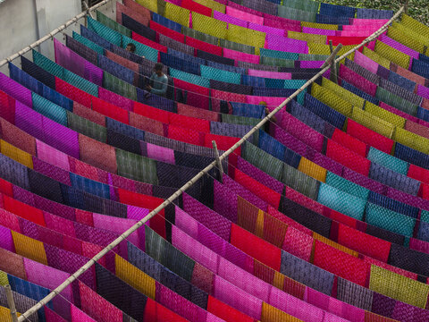 Narayanganj, Bangladesh - 08 March 2026: Aerial view of vibrant textiles drying under the sun, a kaleidoscope of colors creating a mesmerizing pattern.